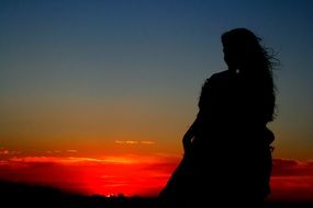 the darkened silhouette of the girl on a sunset background