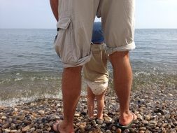 dad with a baby on a pebble beach by the sea
