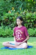 Buddhist girl meditating among the plants in Thailand