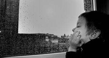 photo of a child at the window during the rain