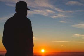 silhouette of a guy in a cap at sunset