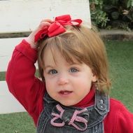 portrait of little girl with a red bow on her head in the street