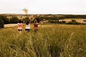 girls with balloons among the meadow