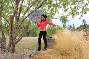 girl balancing on tree with umbrella