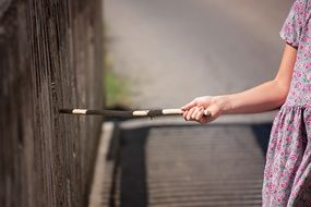 girl with stick near fence