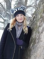 cute blonde in cap with pompons in winter