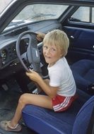 blond child driving car