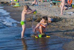 children play with sand by the river