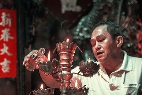 man lighting candles in vietnam