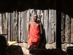 African warrior stands near a wooden wall