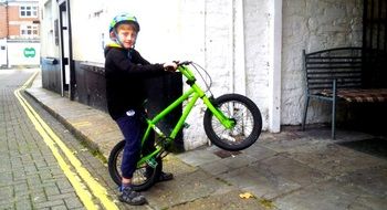 child on a green bike on a city street