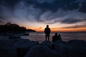 Photo of resting group of people on the beach at sunset