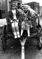Black and white photo of two child girls sitting on cart, vintage