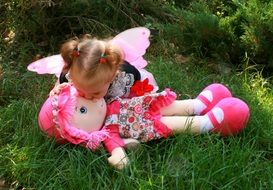 little girl near a doll on green grass