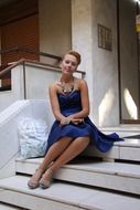 girl in a blue dress sits on the steps