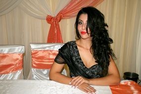 girl with long hair in a black dress on a background of the restaurant atmosphere