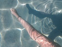 womanâs leg in clear water with shadow on it