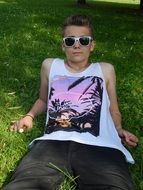 young boy in sunglasses laying on lawn at summer