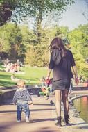 mother and child walk in the park among colorful plants