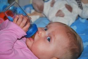 baby girl drinks from a bottle