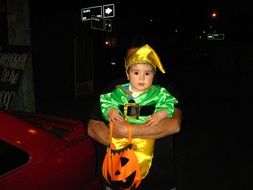 baby boy in colorful costume in manâs hands