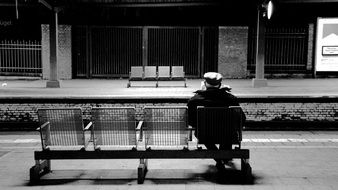 Black and white photo of old man on a train station