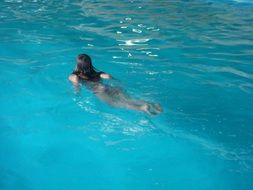 long haired girl swimming in blue pool