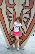 Asian girl on a wall background with a hieroglyph