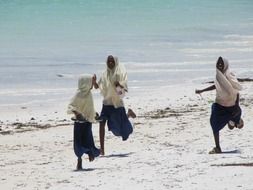 Muslim girls run along the beach near the sea