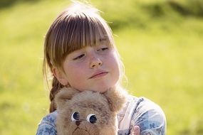 little girl with a teddy bear on the street