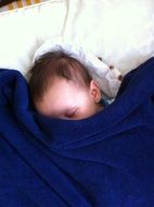 little baby sleeping under a blanket