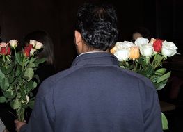 A man holds two bouquets of roses in his hands