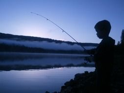 child boy fishing at dusk, usa, california, oakhurst