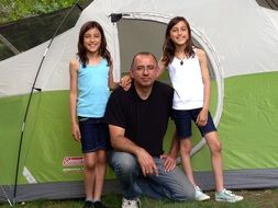 happy family at camping, man and two girls at tent