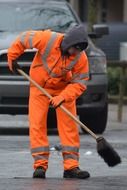 man in the orange uniform cleans with brush