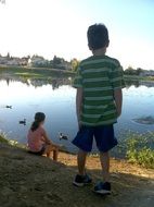 boy and girl watch the ducks from the shore