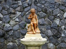 sculpture of a child near a stone wall