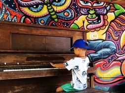 child boy playing piano at bright painted wall