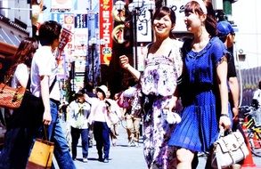 two happy japanese women on busy street, japan, osaka