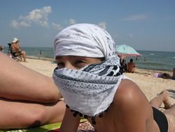 child in balaclava on a sunny beach