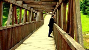 man looking at park from wooden bridge