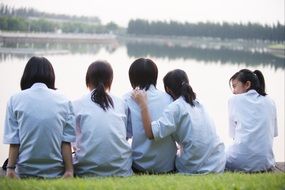 five asian child girls sit together in front of water