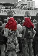 children in red clothes on the shoulders of parents