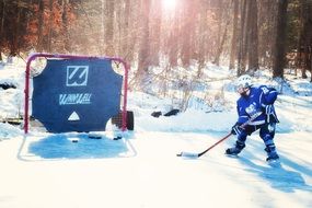 Young hockey player playing hockey outdoors in the glare of the sun