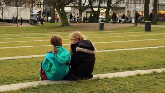 two girls sit together in park