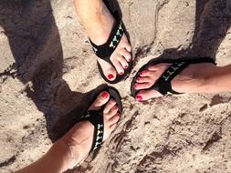 women’s feet in sandals on sand
