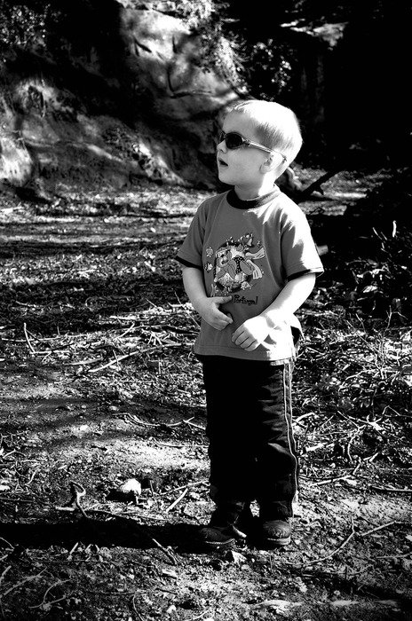 Black and white photo of the small child boy in sunglasses outdoor