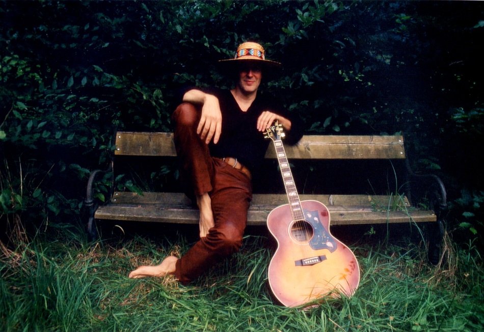 musician with a guitar on a wooden bench