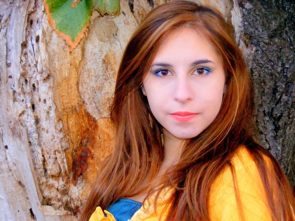 Girl with brown hair and beautiful eyes near a tree