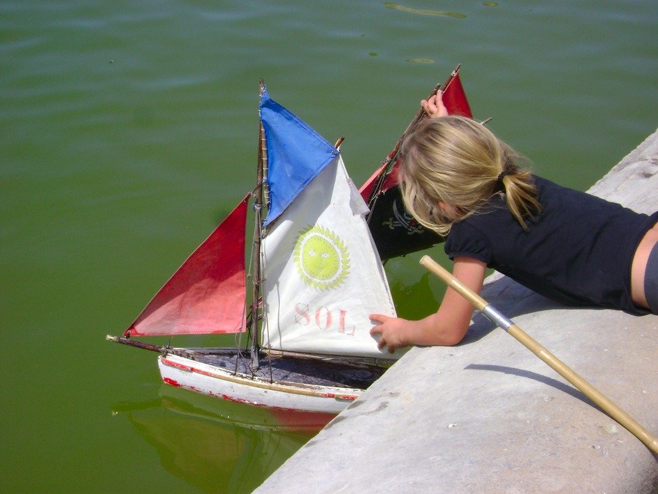 the child launches a toy sail to the water